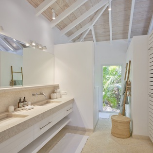 Step into your private spa-like retreat with soaring vaulted ceilings, natural stone vanity, and bright tropical views through the window.