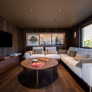 Unwind in your sophisticated living room with rich wood accents, plush seating, and stunning nautical artwork creating the perfect retreat.