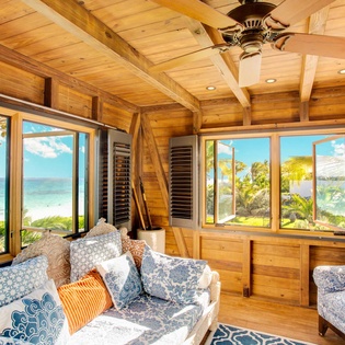 Relax in your sunlit haven with sweeping ocean views, where vaulted wood ceilings and coastal-inspired décor invite you to unwind in pure island comfort.