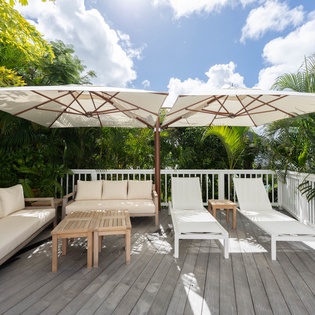 Unwind on your private deck with plush seating and sun loungers, perfectly shaded by tropical palms and endless blue skies.