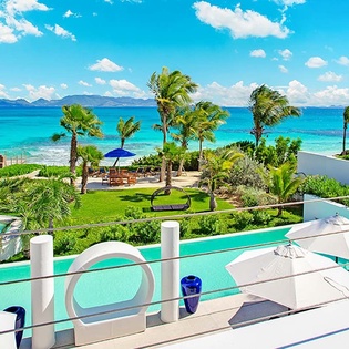 Beachfront paradise with turquoise waters, swaying palms, and pristine pool—an idyllic Caribbean escape framed by lush gardens and stunning coastal views.