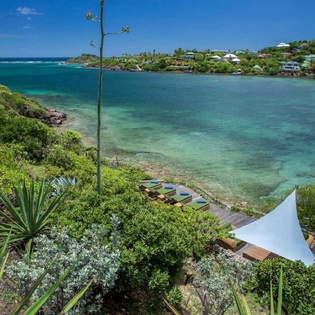 The property offers direct access to a secluded cove with crystal-clear turquoise waters, lush tropical gardens, and a private waterfront setting perfect for relaxation.