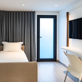 Unwind in your sleek modern retreat with crisp white linens, a wall-mounted TV for entertainment, and convenient workspace perfect for both rest and productivity.