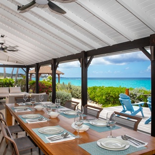Picture yourself dining under a covered patio overlooking turquoise waters and lush greenery. A perfectly set table invites you to savor meals while gentle sea breezes and stunning ocean views create an unforgettable island escape.
