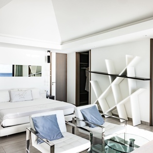 Your stylish suite features crisp white linens, modern seating, and an elegant geometric headboard that creates the perfect sanctuary for relaxation.