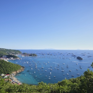 Stunning aerial view showcases the pristine coastline and turquoise waters dotted with sailboats near the property.