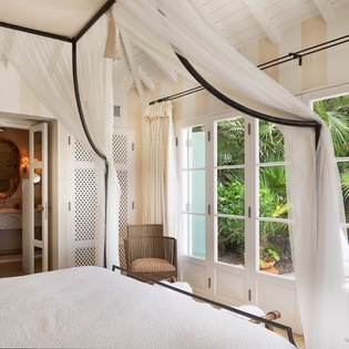 Drift off beneath flowing canopy curtains while lush tropical palms frame your window views. Your serene retreat includes an ensuite bath for total relaxation.