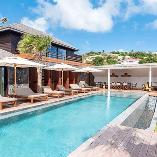 Stunning hillside villa featuring a pristine infinity pool, spacious sun deck with loungers, and covered dining pavilion—an ideal tropical retreat for relaxation and entertaining.