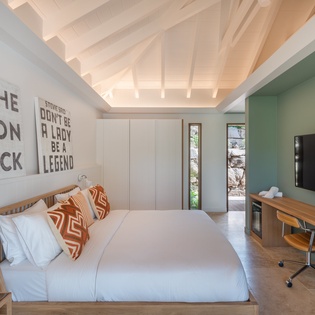 Drift off under exposed wooden beams in your stylish bedroom, where crisp linens meet warm woods and inspiring wall art.