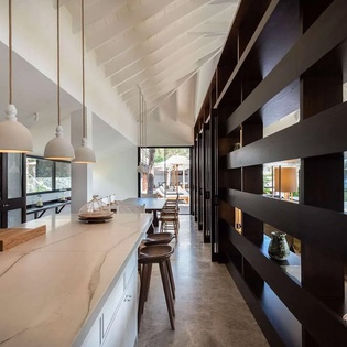 Step into this light-filled open kitchen where vaulted ceilings and sleek modern shelving create an effortless blend of style and function for your culinary adventures.