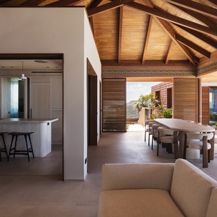 Relax in your open living space where rustic ceiling beams meet modern comfort, seamlessly connecting to a dining area.