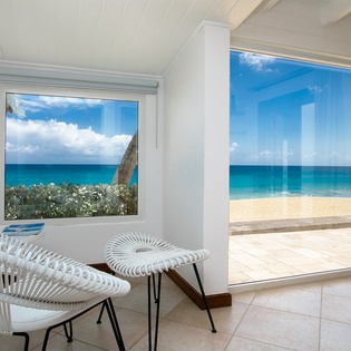 Step into your personal paradise where the turquoise sea meets pristine sand just beyond your window. Relax in the bright, airy seating area and soak in stunning ocean views from two expansive windows—your front-row seat to Caribbean beauty.