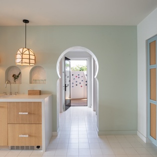 Unwind in your stylish kitchen featuring warm wood cabinetry, elegant pendant lighting, and distinctive Moorish archway leading to your private spaces.