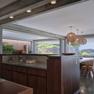 Your open-plan kitchen flows seamlessly into the dining area, where warm pendant lights create intimate ambiance for meals with stunning water views.