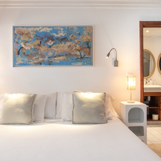 Sink into plush linens under soft lamplight, with vibrant artwork above your bed and your private ensuite bath just steps away.