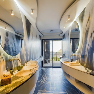 Step into your artistic sanctuary with flowing marble walls, gold fixtures, and dramatic mirrors creating a spa-like retreat for your morning routine.