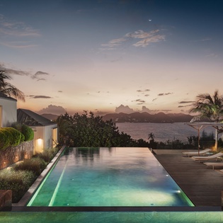 Luxurious infinity pool overlooking ocean and mountain views at this stunning tropical property during golden hour.