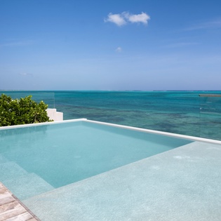 Stunning infinity pool overlooking turquoise Caribbean waters creates the perfect tropical escape for your oceanfront getaway.