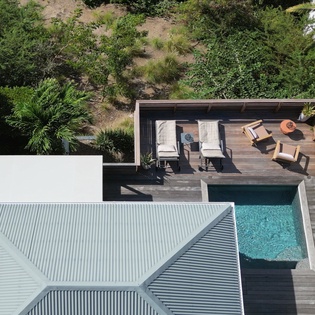 Aerial view reveals a modern villa with private pool, deck seating, and tropical landscaping for ultimate relaxation.