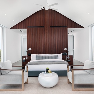 Unwind in your serene sanctuary with floor-to-ceiling windows, contemporary furnishings, and a striking wood accent wall creating the perfect retreat.