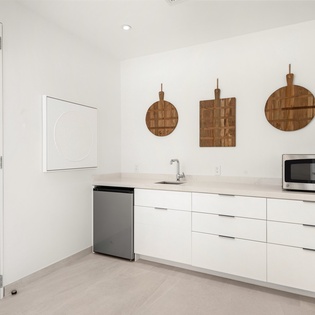 Your sleek kitchen features modern white cabinetry, stainless steel appliances, and stylish wooden cutting boards ready for your culinary adventures.