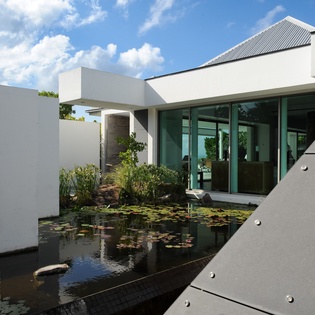 Modern architecture meets tranquil water features at this stylish property entrance with lily pond.