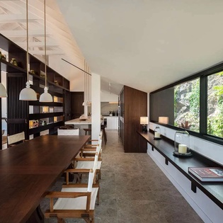 Your bright, open living space blends sleek design with natural warmth, featuring a long dining table perfect for gatherings and lush garden views.