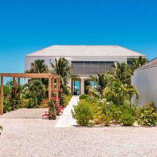 A stunning contemporary villa with pristine white architecture and lush tropical gardens creates an elegant arrival experience.