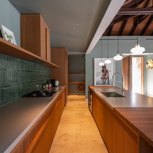 Your gourmet kitchen features rich wood cabinetry, emerald tiles, and a spacious island perfect for cooking memorable meals together.