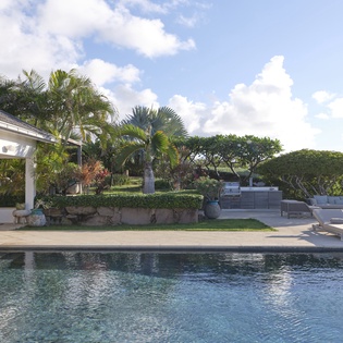 Settle into a sun lounger beside your sparkling pool, surrounded by lush tropical palms and open skies—perfect for lazy afternoons and warm island breezes.