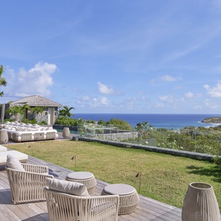 Luxury villa with stunning ocean views, private lawn, and elegant outdoor seating overlooking turquoise waters.