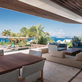 Unwind in your covered terrace where ocean breezes flow through modern seating areas, perfect for dining or lounging while gazing at endless Caribbean blues.