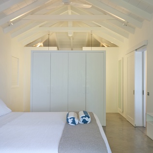 Your serene bedroom sanctuary features exposed wooden beams and crisp white linens under dramatic vaulted ceilings.