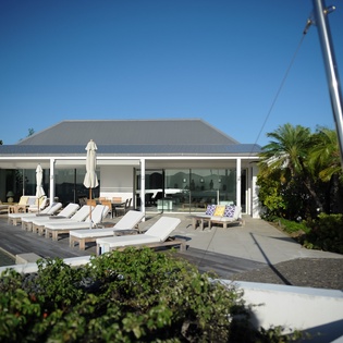 Modern tropical villa with pool, sun loungers, and lush palm trees creating a serene island paradise.