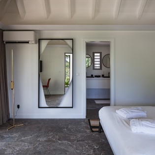 Relax in your spacious bedroom with exposed beams, air conditioning, and garden views through floor-to-ceiling windows.