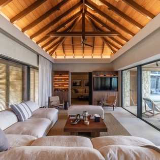 Unwind in your stunning living room with soaring wooden beams and floor-to-ceiling windows that flood the space with natural light.