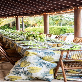 Gather for memorable meals at this stunning outdoor dining pavilion, where tropical elegance meets comfort beneath warm string lights.