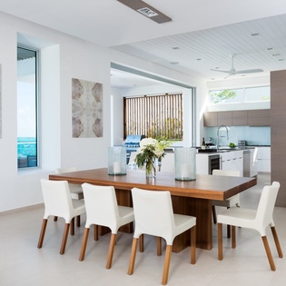 Gather around this stunning dining table where ocean views frame your meals in this bright, modern space.