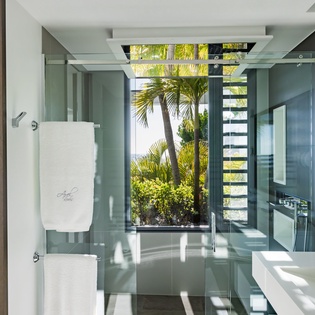 Immerse yourself in this stunning glass-walled bathroom where tropical views and modern luxury merge seamlessly into your daily routine.