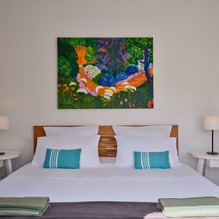 Sink into crisp white linens beneath vibrant tropical artwork in your peaceful bedroom retreat.