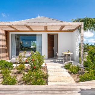 Modern tropical villa with pergola and private terrace surrounded by lush landscaping and palm trees.