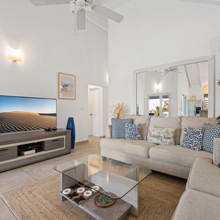 Relax in your stylish living room with modern furnishings, large TV, and tropical touches creating the perfect vacation vibe.