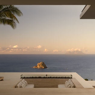 Unwind in your private seating area while watching the golden hour paint the ocean, with a small rocky island adding charm to your panoramic sea view.