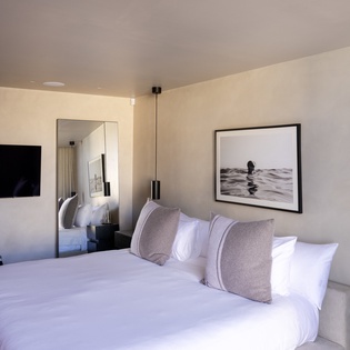 Sink into crisp white linens and modern comfort. Your sophisticated bedroom features sleek pendant lighting and coastal artwork for the perfect retreat.