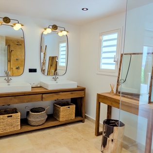Refresh in your serene bathroom featuring dual sinks, warm wood accents, and a bright walk-in shower. Natural light flows through the window, creating a spa-like retreat where you can unwind after a day of island adventures.