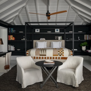 Unwind in your sophisticated suite featuring exposed beams, built-in library shelves, and a cozy seating area perfect for evening relaxation.