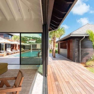 Seamless indoor-outdoor living opens to a sun-drenched deck, sparkling pool, and tropical palms—your private escape in paradise.