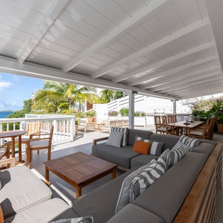 Relax on your expansive covered terrace with plush seating and stunning ocean views through swaying palms.