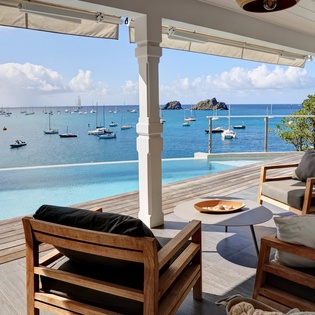 Elegant waterfront terrace with infinity pool overlooking pristine harbor and distant islands.