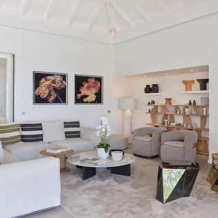 Settle into your serene living space where vaulted ceilings, curated artwork, and plush seating create an airy, sophisticated retreat. Unwind here with a book or conversation in elegant comfort.